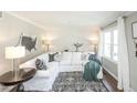Inviting living room showcasing a white sectional, decorative pillows, and a bright window with white curtains at 1288 Gambel Oaks Dr, Elizabeth, CO 80107