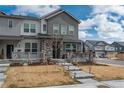 Attractive townhouse showcasing a welcoming porch, stone detailing, and well-maintained landscaping at 688 N Bersshine Ct, Watkins, CO 80137