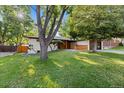Attractive home with a lush green lawn, mature trees, and contemporary wood and painted brick details at 7036 S Apache St, Littleton, CO 80120