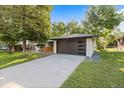 A modern garage with a sleek dark door, set against a well-maintained lawn and blue sky backdrop at 7036 S Apache St, Littleton, CO 80120