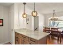 Kitchen island with granite counters, wood cabinets, and pendant lighting with view to dining area at 7192 S Vine E Cir, Centennial, CO 80122