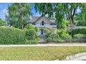 Charming home is surrounded by mature landscaping, a low fence, and a green hedge at 7011 Grandview Ave, Arvada, CO 80002