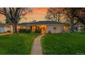 Charming single-story home at sunset with lush green lawn and walkway with landscaped garden at 1935 Oneida St, Denver, CO 80220