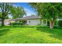 Beautifully landscaped front yard with lush green grass and mature trees surrounding the charming home at 1935 Oneida St, Denver, CO 80220