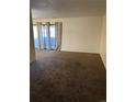 Empty living room with plush carpet, curtains, and sliding glass doors at 10792 E Exposition Ave # 352, Aurora, CO 80012