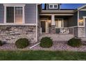 Inviting front entrance with decorative railing, stone accents, and a well-manicured lawn at 11560 Kalispell St, Commerce City, CO 80022