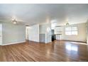 Spacious open-concept living area with hardwood floors, neutral paint, and kitchen access at 7704 Newland St, Arvada, CO 80003