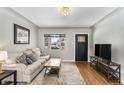 Comfortable living room featuring hardwood floors, a decorative rug, and a wall-mounted television at 1534 Rosemary St, Denver, CO 80220