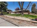 Well-kept brick home featuring a charming front yard and mature trees under a sunny, blue sky at 12375 W 19Th Pl, Lakewood, CO 80215
