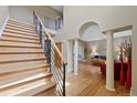 Elegant foyer with wood floors, a staircase with metal railings, and arched doorways to the living spaces at 9 Amaranth Dr, Littleton, CO 80127