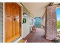 Inviting front porch featuring a wooden deck, brick columns, and a cozy seating area with a view at 9 Amaranth Dr, Littleton, CO 80127