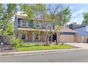 Inviting two-story home with a brick and blue facade, complemented by a lush green lawn and mature trees at 3238 W 11Th Avenue Pl, Broomfield, CO 80020