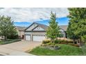 Inviting home with lush green lawn and landscape beds, brick details, and a three-car garage at 21064 Woodside Ln, Parker, CO 80138