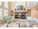 Cozy living room featuring built-in shelving, a stone fireplace, and large windows at 7035 S Picadilly St, Aurora, CO 80016