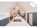 Bright kitchen features a large island with cooktop, marble countertops, and a spiral staircase leading to the upper level at 1165 N Pennsylvania St # 3B, Denver, CO 80203