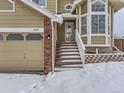 Attractive two-story home with a brick front and attached garage, nestled in a snowy landscape at 1218 Ascot Ave, Highlands Ranch, CO 80126