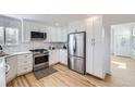 Modern kitchen with white cabinets, stainless steel appliances, and light wood floors at 1218 Ascot Ave, Highlands Ranch, CO 80126