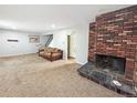 The carpeted living room has a brick fireplace and neutral walls, with a staircase visible in the background at 4777 S Olathe St, Aurora, CO 80015