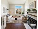 Bright living room with a large window, hardwood floors, fireplace, and modern furniture at 1885 S Quebec Way # H27, Denver, CO 80231