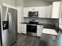 Modern kitchen featuring stainless steel appliances, white cabinets, and black countertops at 15962 E Exposition Dr, Aurora, CO 80017