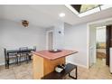 Well-lit kitchen with island and tile flooring; features a skylight and access to a laundry area at 9019 E Oxford Dr, Denver, CO 80237