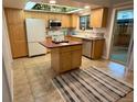 Bright kitchen with light wood cabinets, tile floor, island, white appliances, and unique ceiling detail at 9019 E Oxford Dr, Denver, CO 80237