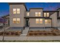 Modern home exterior with neutral siding, a stone base, and a short staircase leading to the front door at 4755 Memphis St # 2, Denver, CO 80239