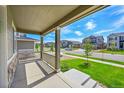Covered front porch offering a view of the lush, green lawn and tree-lined neighborhood street at 821 Boulder Peak Ave, Erie, CO 80516