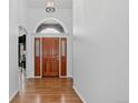 Elegant foyer with hardwood floors, an arched doorway, a wooden door, and white walls, creating a grand entrance at 5926 S Elkhart Ct, Centennial, CO 80016
