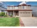 Charming two-story home features a brick facade, covered porch, manicured lawn, and attached two-car garage at 4907 Fenwood Dr, Highlands Ranch, CO 80130