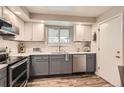Updated kitchen features sleek gray cabinets, stainless steel dishwasher and a sunlit window over a stainless steel sink at 6238 S Cherry Cir, Centennial, CO 80121