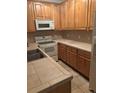 Traditional kitchen featuring wood cabinets, white appliances, and tile countertops at 16366 E Fremont Ave # 11, Aurora, CO 80016