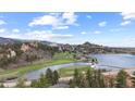 Expansive aerial view of golf course and lake next to mountains and trees at 7267 Comanche Ct, Larkspur, CO 80118