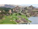 Scenic golf course with lush green fairways, mature trees, and serene water features nestled in a mountain landscape at 7267 Comanche Ct, Larkspur, CO 80118