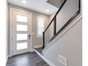 Inviting entryway with wood-look floors, a modern front door, and a stylish staircase leading to the upper level at 2648 Mayotte Way, Castle Rock, CO 80109