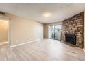 Inviting living room with a stone fireplace, neutral walls, and light wood floors at 11937 E Harvard Ave # 102, Aurora, CO 80014