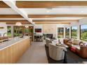 Open-concept living room featuring wood beams, fireplace, and sliding doors to the backyard at 11900 W 18Th Ave, Lakewood, CO 80215