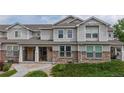 Inviting townhome exterior featuring stone accents, well-maintained landscaping, and covered front porch at 9758 Laredo St # 22D, Commerce City, CO 80022