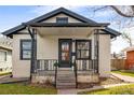Charming bungalow with wrought iron porch railing, stucco siding, and black trim on a landscaped lot at 2676 S Lincoln St, Denver, CO 80210