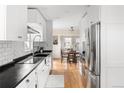 Bright kitchen featuring white cabinets, stainless steel appliances, and a view of the dining area at 2676 S Lincoln St, Denver, CO 80210