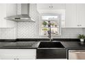 Modern kitchen featuring white subway tile backsplash, black countertops and window plants at 2676 S Lincoln St, Denver, CO 80210