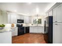 Modern kitchen featuring white cabinets, dark appliances, hardwood floors, and a bright window at 3285 Balsam St, Wheat Ridge, CO 80033