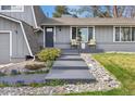 Inviting home entrance featuring a modern walkway, manicured landscaping, and a charming seating area on the porch at 2477 S Dover Way, Lakewood, CO 80227
