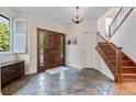 Inviting foyer with stone tile flooring, a wooden staircase, and a chandelier for a touch of elegance at 2400 S Clayton St, Denver, CO 80210