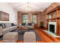 Bright living room featuring exposed brick, wood floors, a fireplace, and a stylish chandelier at 1210 E Colfax Ave # 302, Denver, CO 80218