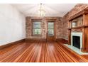 Empty living room showcasing hardwood floors, exposed brick, a fireplace, and natural light at 1210 E Colfax Ave # 302, Denver, CO 80218