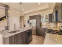 This modern kitchen features stainless appliances, dark wood cabinets, granite counters, and an island at 2114 N Clay St, Denver, CO 80211