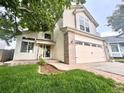Two-story home featuring a front yard with brick accents on the garage and entryway at 10064 Westside Cir, Littleton, CO 80125