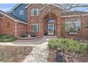 Close up of the front entrance featuring a brick archway, glass door, and well-manicured landscaping at 21166 E Euclid Dr, Centennial, CO 80016