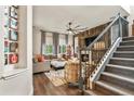 Inviting living room with a stone fireplace, wood-paneled wall, and staircase at 6471 S Potomac Ct, Englewood, CO 80111